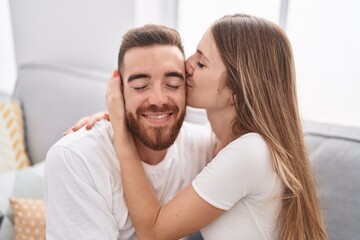 Man and woman couple sitting on sofa kissing at home
