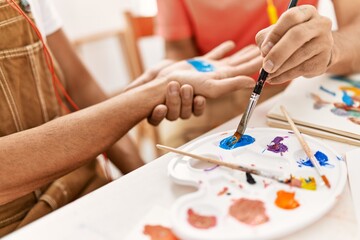 Naklejka premium Two hispanic men couple painting palm hands at art studio