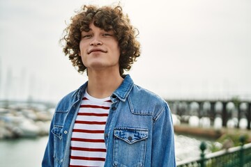 Young hispanic man smiling at marina port