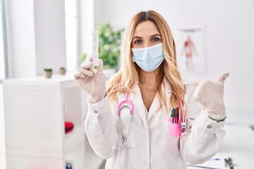 Naklejka premium Young caucasian doctor woman holding covid test pointing finger to one self smiling happy and proud