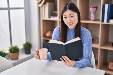 Chinese woman reading book and drinking coffee at home