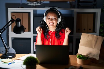 Young asian woman working at the office with laptop at night celebrating crazy and amazed for success with arms raised and open eyes screaming excited. winner concept