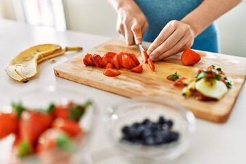 Obraz na płótnie Canvas Young woman cutting strawberry at kitchen