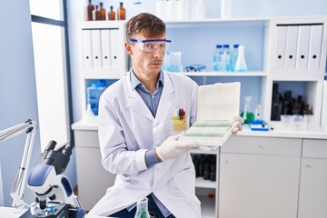 Caucasian man working at scientist laboratory smiling looking to the side and staring away thinking.