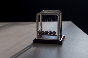 A pendulum made of metal balls on a fishing line in the office to calm the nerves
