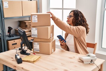 Middle age hispanic woman working with parcels at ecommerce