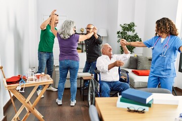 Group of retired people having party dancing with doctor and volunteer at nurse home.