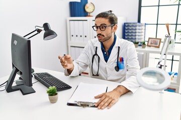 Handsome hispanic man working as doctor speaking to a patient at hospital clinic