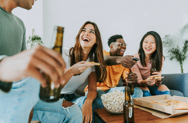 Group of friends watching tv and eating pizza - Multiracial cheerful young people having weekend...