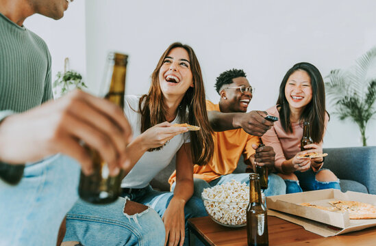 Group of friends watching tv and eating pizza - Multiracial cheerful young people having weekend home party together - Happy students having fun in university rooms - Youth lifestyle and food concept