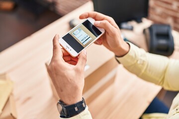 Young hispanic man ecommerce business worker scanning label using smartphone at office