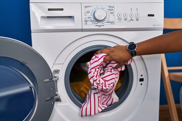 Young beautiful latin woman washing clothes at laundry room