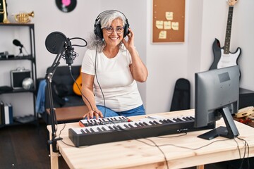 Middle age woman musician playing keyboard piano at music studio