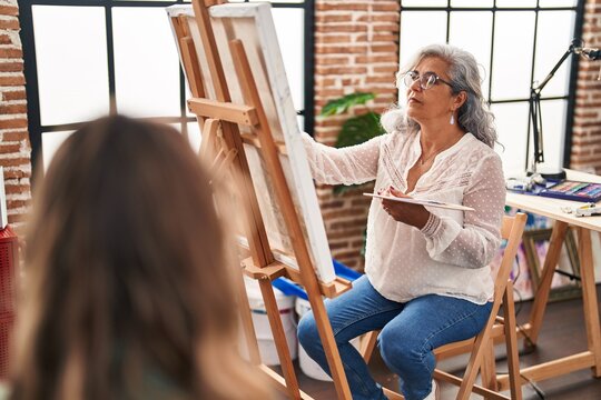Middle age woman artist drawing portrait of person at art studio