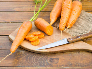 Fresh organic carrots with green leaves on wooden background. Vegetables.