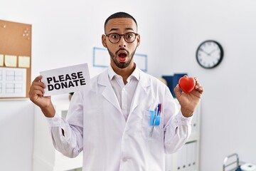 African american doctor man supporting organs donations in shock face, looking skeptical and...