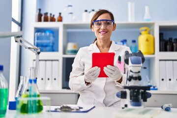 Middle age woman wearing scientist uniform using touchpad at laboratory
