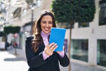 Young hispanic woman smiling confident using touchpad at street