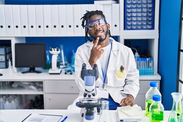African man with dreadlocks working at scientist laboratory smiling looking confident at the camera...