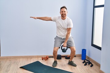 Fototapeta premium Young caucasian man smiling confident using kettlebell training at sport center