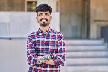 Fototapeta premium Young hispanic man smiling confident standing with arms crossed gesture at street