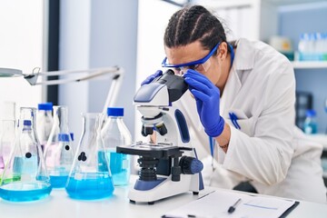 Young man wearing scientist uniform using microscope at laboratory