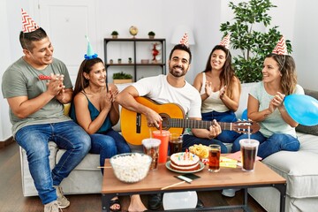 Group of young hispanic friends having birthday party playing spanish guitar at home.