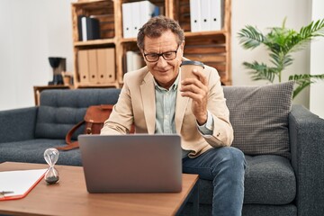 Middle age man having psychology session using laptop drinking coffee at clinic