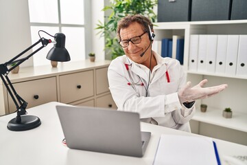 Senior doctor man working on online appointment pointing aside with hands open palms showing copy space, presenting advertisement smiling excited happy
