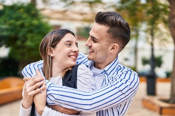 Fototapeta premium Man and woman couple smiling confident hugging each other at park