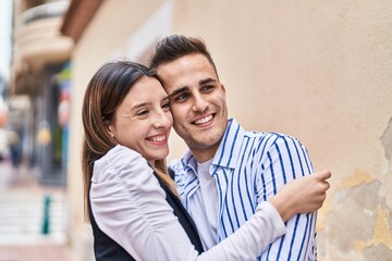 Man and woman couple smiling confident hugging each other at street