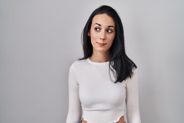 Obraz premium Hispanic woman standing over isolated background smiling looking to the side and staring away thinking.
