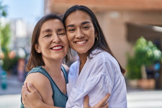 Two women mother and daughter smiling confident hugging each other at street