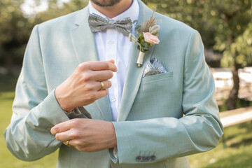 Nahaufnahme von einem Bräutigam, der sein Anzug zuknöpft