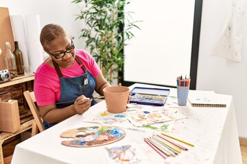 Senior african american woman smiling confident painting clay ceramic at art studio