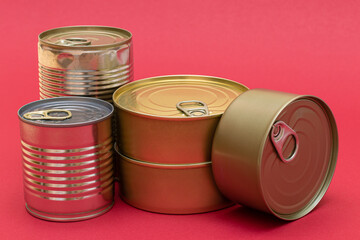 A Group of Stacked Tin Cans with Blank Edges on Red Background. Canned Food. Different Aluminum Cans for Safe and Long Term Storage of Food. Steel Sealed Food Storage Containers