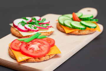 Different Cracker Sandwiches with Tomato, Cucumber, Radish and Cheese on Cutting Board. Easy Breakfast. Diet Food. Quick and Healthy Sandwiches. Crispbread with Tasty Filling. Healthy Dietary Snack