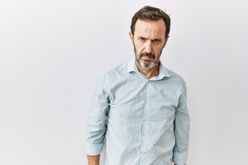 Middle age hispanic man with beard standing over isolated background skeptic and nervous, frowning upset because of problem. negative person.