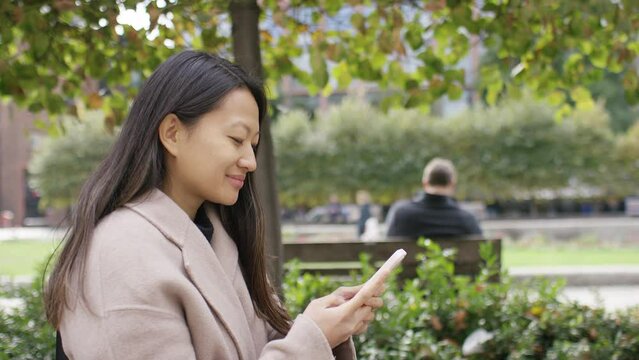 Attractive young female walking through the city using her phone, in slow motion