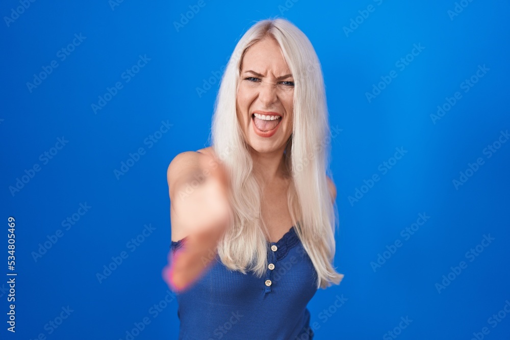 Canvas Prints Caucasian woman standing over blue background pointing displeased and frustrated to the camera, angry and furious with you