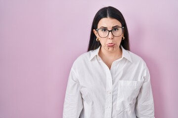 Young brunette woman standing over pink background depressed and worry for distress, crying angry and afraid. sad expression.