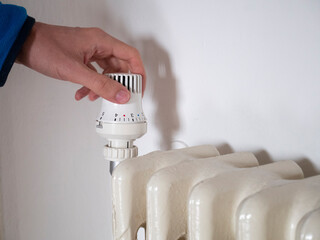Hand turns on the radiator knob. Adjust the house temperature. Radiator valve. Gas crisis. Heating...