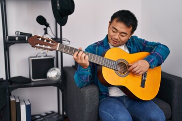 Young chinese man guitarist playing classical guitar at music studio