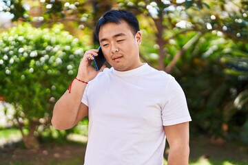 Young chinese man talking on the smartphone at park