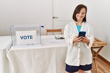 Brunette woman with down syndrome smiling using smartphone at election room