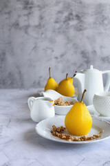 Delicious homemade autumn dessert: pears boiled in white wine. Pears in white wine with caramel on a light marble table. Light fruit dessert. Place for text. Vertical photo. 