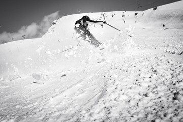 Dynamic picture of a skier on the piste in Alps. Woman skier in the soft snow. Active winter...
