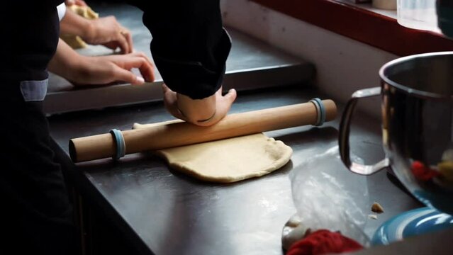 Close-up video of a rolling pin kneading dough. Unrecognizable person.