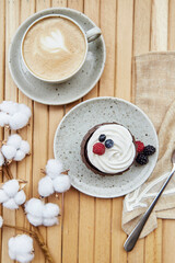 Tender french cupcake with cup of coffee outside. Atmospheric cotton decoration. Cozy breakfast at the terrace, guilty pleasure