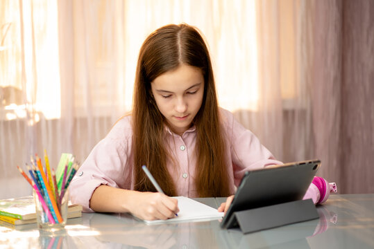 A teenage girl learns online from home. Education.